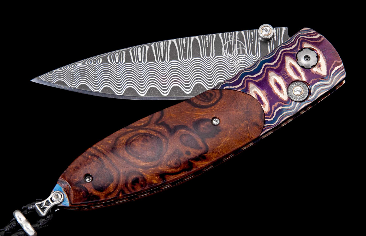 William Henry Studio Knife Frame Type: Wave' mokume, inlaid with desert ironwood
Blade Type: Wave' damascus steel with an extra strong core in VG-10
Number: 039/100
Gemstones/Embellishments: white topaz gemstones