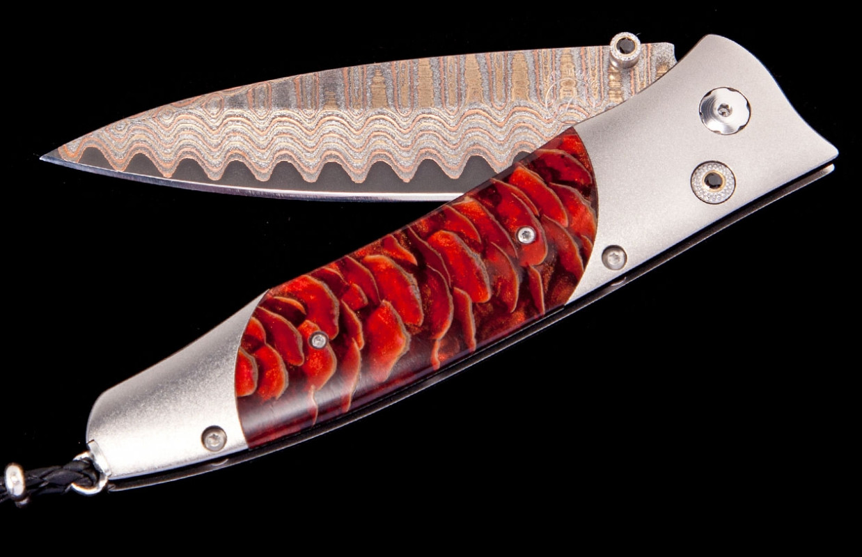 William Henry Knife Frame Type: Aerospace Grade Titanium
Blade Type:  'Copper Wave' Damascus With A Core Of Vg5 Steel
Scale/Inlay: Inlaid With Stabilized Blue Spruce Pine Cone
Serial: 2130-0260 
Number: 139/250
Gemstones/Embellishments: Spinel