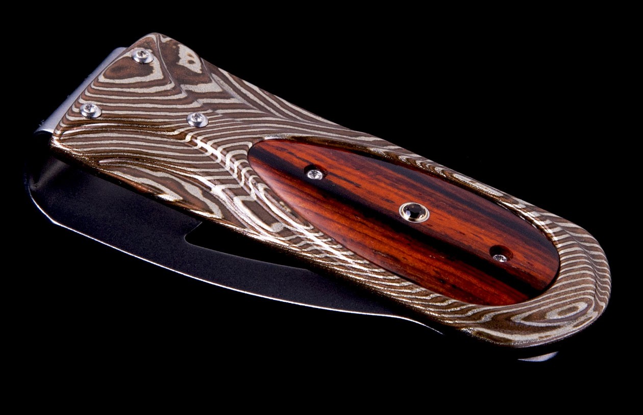 William Henry:  Money Clip Frame/Body: Twist Mokume Gane, Hand-Forged by Mike Sakmar
Scale/Inlay: Cocobolo Wood
Gemstones/Embellishments: Smoky Quartz
Number: # 737/988